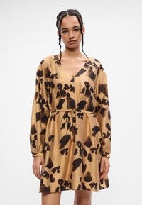 Φόρεμα με λεοπάρ σχέδιο σε μπεζ χρώμα, με μακριά μανίκια, βαθύ V-ντεκολτέ, σφιχτή μέση και απαλό ύφασμα. Διαθέτει ζώνη τύπου φιόγκο και χαλαρή εφαρμογή.