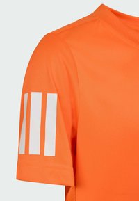 Oranžové sportovní tričko s hladkým povrchem. Obsahuje tři bílé vertikální pruhy na rukávu a design s kulatým výstřihem.