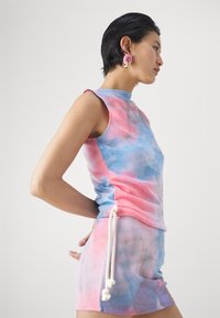 Kleurrijke tweedelige outfit met een mouwloze top en een shortset. Het materiaal is zacht met een tie-dye patroon in roze en blauwe tinten.