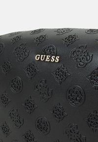Borsa a mano nera in ecopelle con motivi in rilievo e logo dorato "GUESS". Tessuto liscio con dettagli di design intricati in tutto.