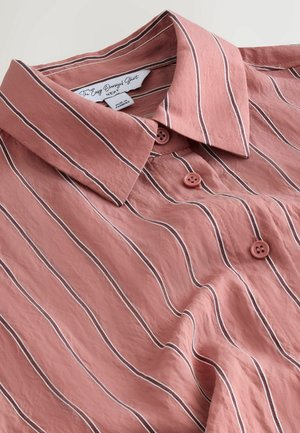 Rózsaszín, gombos, fehér és barna függőleges csíkos ing hegyes gallérral, "The Easy Oversized Shirt" felirattal.