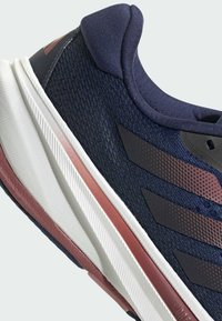 Navy athletic shoe featuring a breathable mesh upper, white midsole with textured grooves, and maroon accents along the sole.