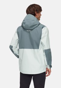 Veste imperméable en bleu clair et gris. Présente une capuche, un design bicolore et des poignets ajustables. Logo au dos.