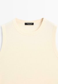 Top senza maniche color beige con tessuto morbido, caratterizzato da un'etichetta nera cucita all'interno del collo.