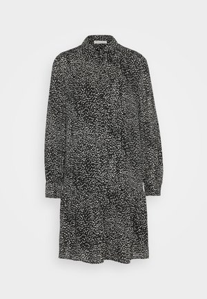 Rochie neagră cu mâneci lungi și guler, având un model alb cu pete și o margine evazată. Țesătură ușoară cu o textura netedă.