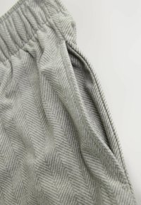 Grau gestreifter Stoff im Fischgrätenmuster mit weicher Textur, ausgestattet mit einem elastischen Bund und sichtbaren Nähdetails.