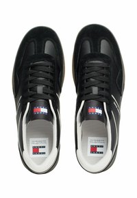 Czarne sportowe buty z zamszu i skóry, z sznurowadłami, białym logo oraz gumową podeszwą.