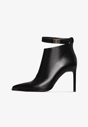 Sorte læder ankelstøvle med spids tå, høj stiletthæl og justerbar ankelrem med en metalbuckle detalje.