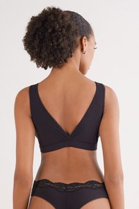 Svart rippad bralette med djup V-öppning bak och spetsdetaljer. Halsringningen har en slät finish och breda, ribbade axelband för stöd.