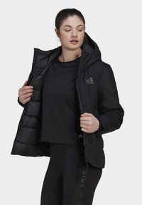 Black puffer jacket with a hood, featuring a zip front and elastic cuffs. The interior has a quilted design and displays the Adidas logo.