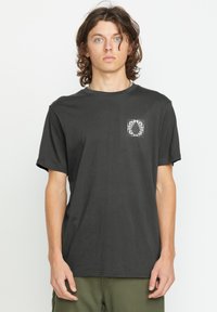 Sort bomulds t-shirt med rund hals, korte ærmer og et trykt grafisk motiv på venstre brystområde. Blød tekstur og afslappet pasform.