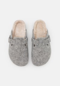 Gray felt clogs with a soft beige lining, designed with a buckle accent and slits for ventilation. Flat soles, rounded toe shape.