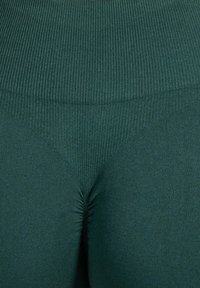 Donkergroene leggings met hoge taille, voorzien van een geribbelde textuur en plooidetail in het midden, met een glad en aansluitend ontwerp.