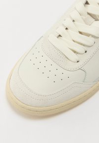 Hvite lær sneakers med beige semsket detaljer, rund tå, perforerte detaljer, flate kremfargede snorer og en teksturert off-white gummisåle.
