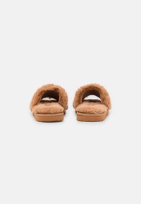 Open-toed slippers with a tan faux fur upper, soft footbed, and flat sole. The design features two wide straps for comfort and support.