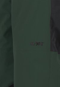 Grüne Oberbekleidung mit schwarzen Akzenten, die ein elegantes Design aufweist. Auffälliges Logo "SLOPE" auf der Vorderseite, glatte Textur und minimalistischer Stil.