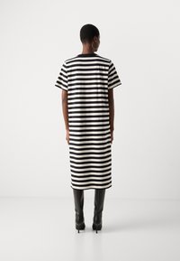 Svart og hvit stripete oversized kjole med korte ermer, som når midt på leggen, parret med stilige svarte knesokker.