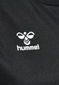 Svart stoff med en jevn tekstur som har en hvit Hummel-logo, bestående av en stilisert bieform og merkevarenavnet under.