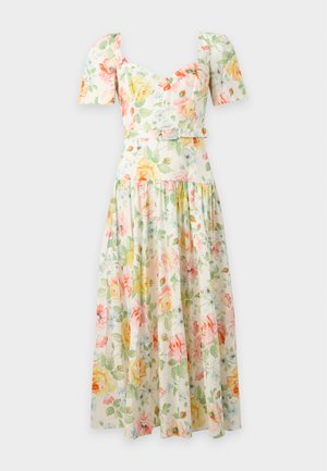 Femme portant une robe midi fleurie avec des manches bouffantes, un décolleté en cœur, une taille ceinturée et des sandales à talons beiges, debout sur fond blanc.