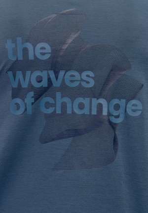 Námornícky modrý materiál s textom "vlny zmien" v modrom gradientu, prekrytý vlnitým vzorom.