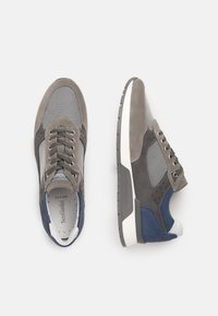 Sneaker grigie e blu navy realizzate in materiali scamosciati e in rete, con design stringato, collare imbottito e dettagli testurizzati sulla suola.