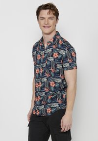 Korte mouwen button-up shirt in marineblauw met tropisch bloemenpatroon, met roze hibiscus bloemen en groene bladeren. Casual fit.