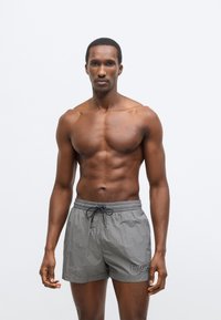 Γκρι μαγιό βερμούδα με υφασμάτινη υφή, ελαστική μέση και κορδόνι. Διαθέτει εμφανές λογότυπο στο αριστερό μ�ηρό.