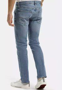 Jasnoniebieskie dżinsy o slim fit, z pięcioma kieszeniami i subtelnym wyblaskiem. W połączeniu z białymi sneakersami z szarymi akcentami.