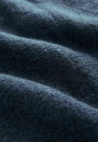 Sötétkék szövet, puha, bolyhos textúrával, finom hullámokkal és könnyű, szőtt megjelenéssel. Nincsenek látható minták vagy fémalkatrészek.