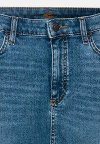 Denim jeans i en medium blå vask med kontrasterende sennepsfarvet syninger. Har en knaplukning og traditionelt fem-lomme design.