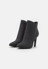 Schwarze Knöchelstiefel aus strukturiertem Stoff, mit spitzer Zehenform und hohem Stiletto-Absatz, in einem eleganten, minimalistischen Design.