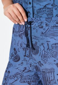 Blauwe geblokte stoffen shorts met een trekkoord in de taille, versierd met schetsachtige illustraties van gebouwen, bomen en waterlandschappen.
