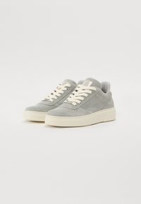 Grå semskede sneakers med rund tå, kremfargede lisser og en teksturert gummisåle. Har perforeringer og en polstret krage for komfort.