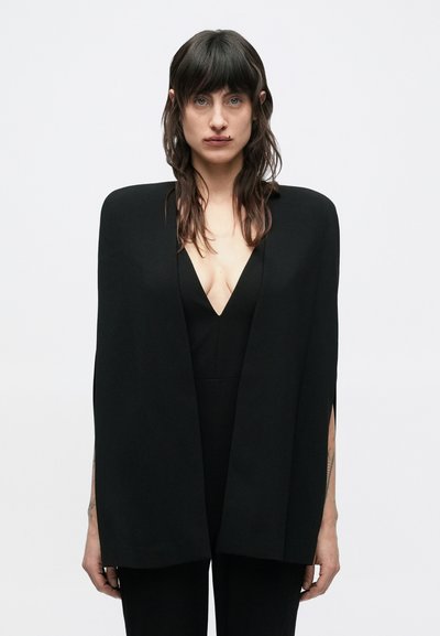 Must varjund, sile kangas, avatud eesmine osa, teravalt määratletud servad, õlakujuaugud, kantud sügava V-kaelusega kombinesooni peale, minimalistlik disain.