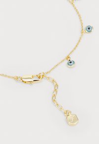 Goldene Kettenhalskette mit blauen, augenförmigen Anhängern, strukturierten Gliedern, einem Karabinerverschluss und einem gravierten sechseckigen Anhänger.