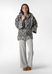 Grå og sort chevron-mønstret fleece hoodie med store ærmer, parret med grå vide bukser og brune slippers.