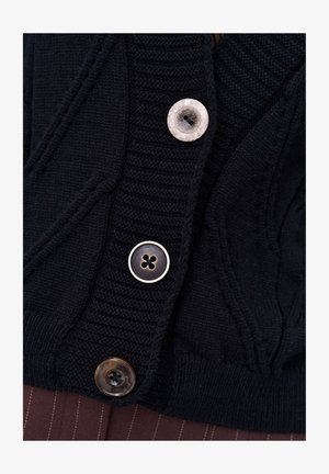 Zwarte gebreide cardigan met ribstructuur, drie knopen in verschillende stijlen: wit, goud en donkerbruin met een ontwerp van vier gaten.