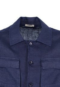 Camicia di lino blu navy con colletto, due tasche sul petto e bottoni arrotondati. Tessuto testurizzato con un aspetto leggermente stropicciato.