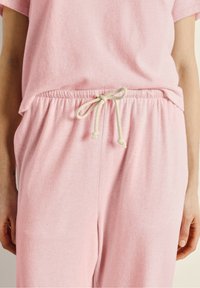 Ensemble de vêtements d'intérieur rose avec un haut à manches courtes décontracté et un pantalon à taille élastique avec cordon de serrage. Matière en coton doux, texture légère.