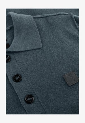 Donker teal gebreide polo shirt gemaakt van zachte stof, met een kraag, drie zwarte knopen en een gestructureerd ontwerp met een klein logo-embleem.