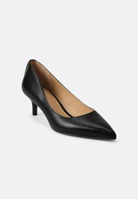 Μαύρο δερμάτινο παπούτσι με μυτερή μύτη και τακούνι kitten, εσωτερική επένδυση σε μπεζ χρώμα, παρουσιάζεται σε λευκό φόντο, στραμμένο προς τα αριστερά.