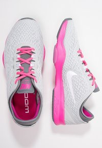 Harmaat verkkokengät vaaleanpunaisilla yksityiskohdilla, joissa on harmaat nauhat, pehmustettu pohja sekä näkyvä logo sivulla ja kielekkeellä.