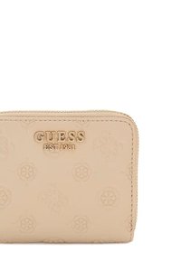 Portafoglio beige con motivo floreale in rilievo, chiusura con zip e logo dorato del marchio "GUESS EST. 1981" sul davanti. Texture liscia.