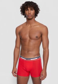 Red cotton boxer shorts with a fitted design and a white waistband featuring navy blue accents and the "Levi's" logo.