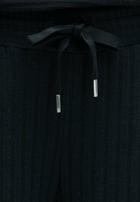 Schwarze strukturierte Hose mit vertikalen Streifen, ausgestattet mit einem elastischen Bund und einem Kordelzug mit silbernen Metallenden.