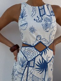 Rochie din material alb, cu modele abstracte albastre, având un corset ajustat și decupaje pe laterale, evidențiată de un detaliu geometric la talie.