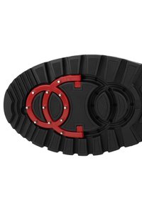 Zwarte rubberen schoenzool met drie rode cirkelvormige logo's, voorzien van gestructureerde groeven en metalen accenten voor grip en ontwerpdetails.