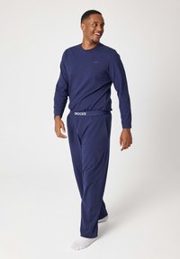 Top a maniche lunghe blu navy e pantaloni abbinati realizzati in tessuto morbido, con una cintura elastica con il logo del marchio e un logo discreto sul petto.
