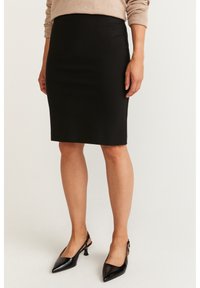 Černá tužková sukně s přiléhavým designem vyrobená z hladkého materiálu. V kombinaci s černými lodičkami na podpatku se špičatou špičkou.