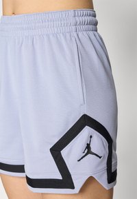 Svijetlo lavanda atletske kratke hlače s teksturiranim materijalom, s crnim Jordan logom i crnim akcentima na rubovima. Uključena elastična traka za struk.